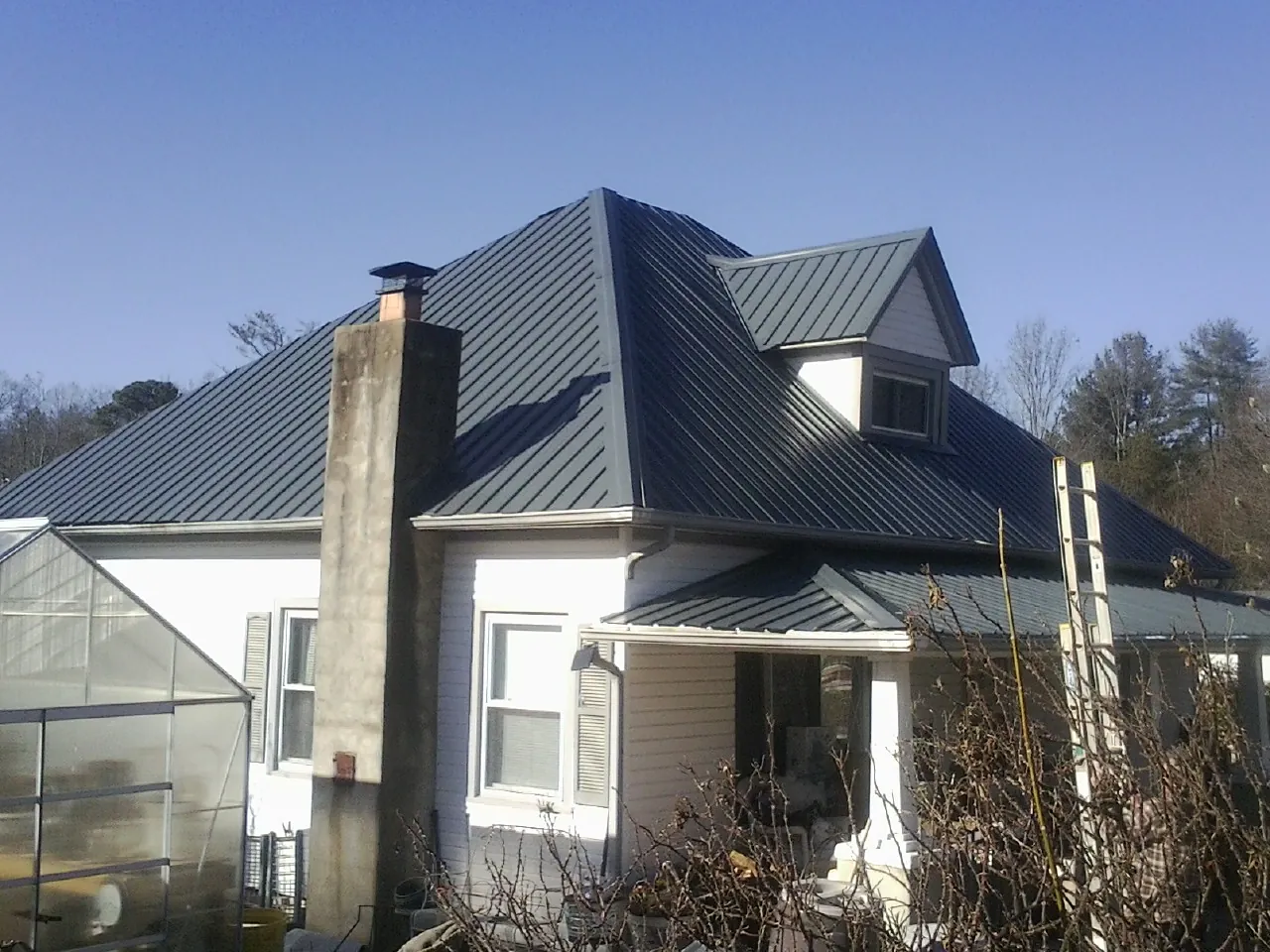 Dark blue standing seam metal roof on a white farmhouse with dormer — Slate & Tile Roof Repair by Roofing Brothers in Moab