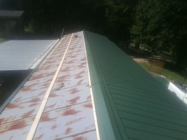 Old rusted panels beside newly installed green metal roofing — Wind Damage Roof Repair by Roofing Brothers in Moab