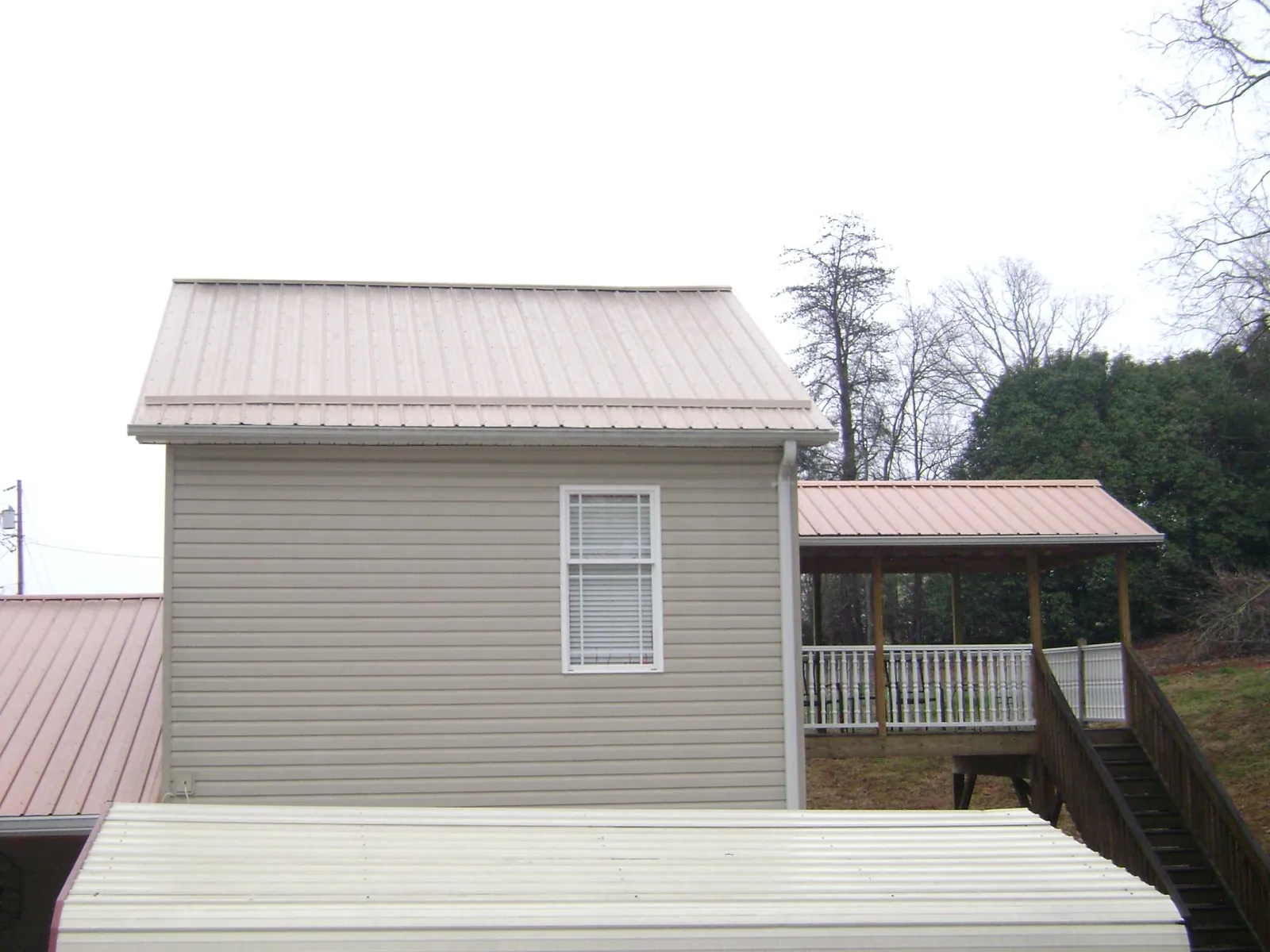 Tan metal roofs on a two story addition and attached porch, from a Roof Replacement job in Moab