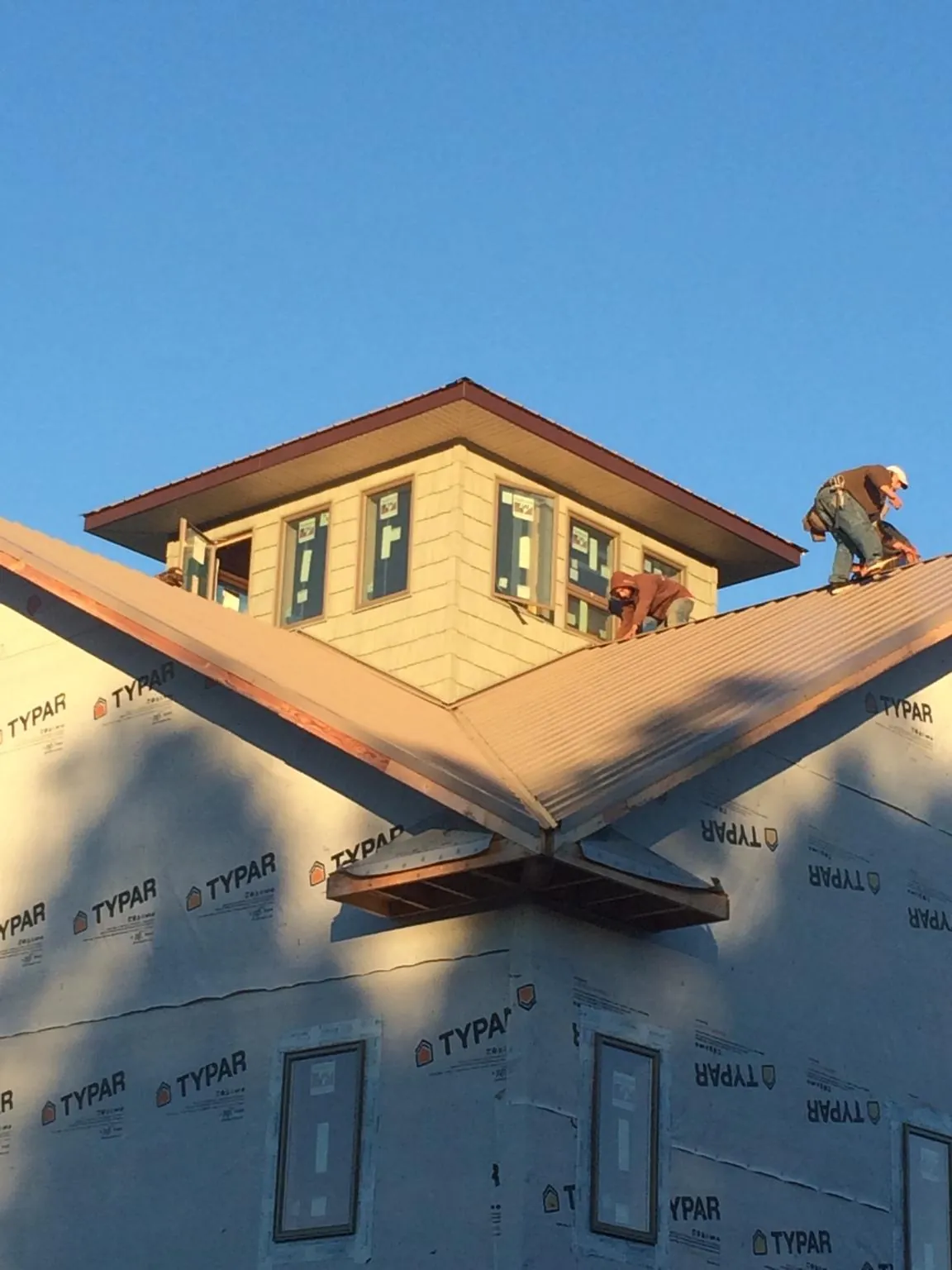 Roofers working around a rooftop cupola on a new metal roof at sunset — Roof Waterproofing in Moab by Roofing Brothers
